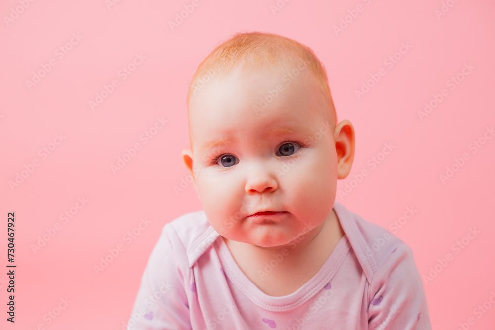 Portrait of a cute baby girl isolated on a pink background.