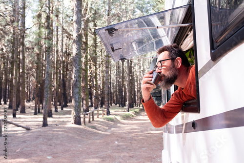 One man enjoying the view outside the window of a motorhome camper van enjoying vanlife and alternative travel vehicle vacation holiday. Freedom. Nomadic lifestyle people fulltimers. Free parking van photo