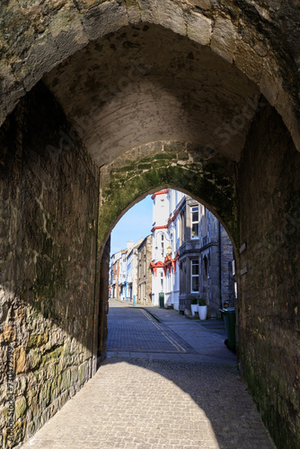 Historic Stone Archway Leading to a Quaint Town Street in Caernarfon photo