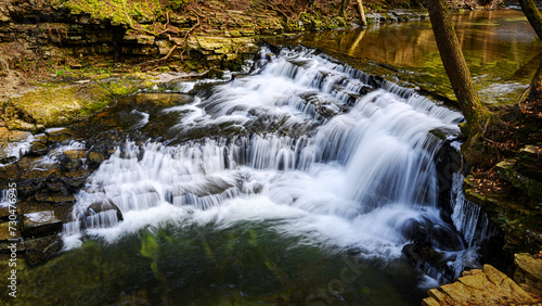 A partially frozen waterfall in late winter. Water rushes over and down the rocks at Salt Springs State Park in Montrose, PA. Heavy ice has already melted due to warmer temperatures.