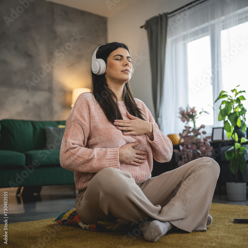 one woman doing guided meditation yoga self care practice at home photo