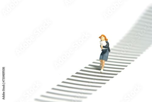 Miniature tiny people toy photography. Front view of a girl pupil student running on zebra crossing crosswalk. Isolated on a white background