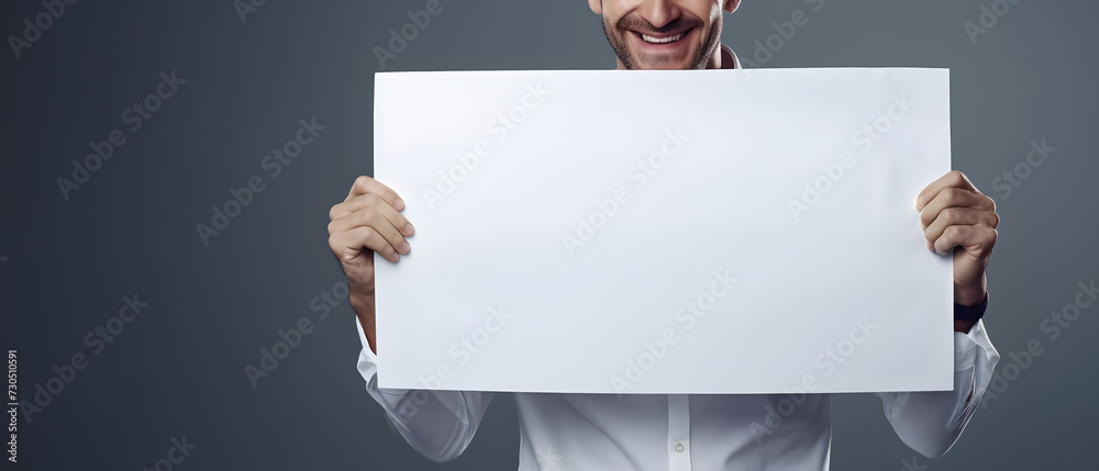 happy man holding a white sign on a gray background - copy space mockup happy man holding a white sign on a gray background - copy space mockup