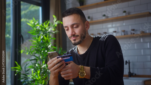 man holding credit card and smartphone enters credit card number to online purchases. Male using instant easy mobile payments, making purchase in online store