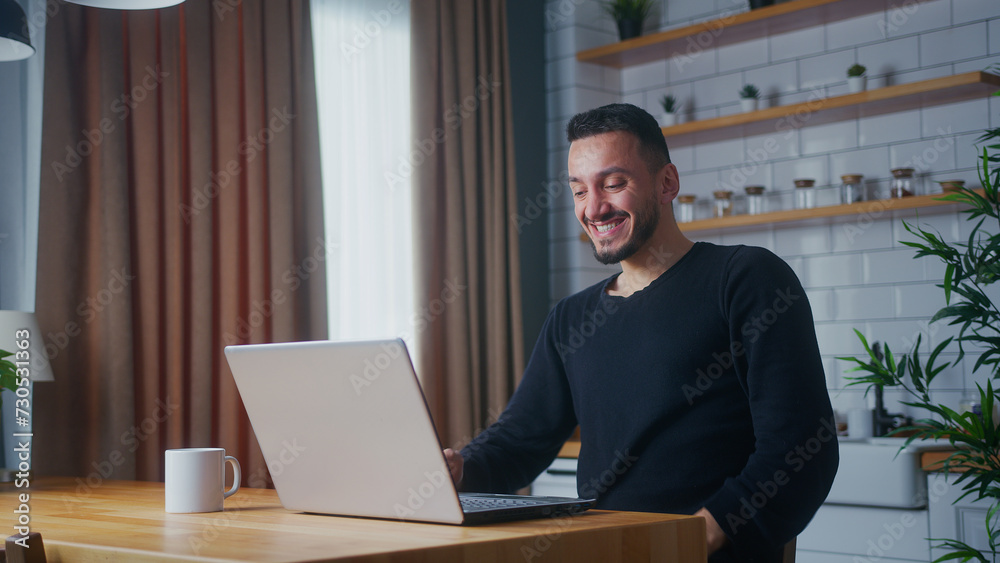 man sitting in the kitchen checking emails read notice receive good news win lottery on laptop celebrate great opportunity feels happy man sitting in the kitchen checking emails read notice receive good news win lottery on laptop celebrate great opportunity feels happy