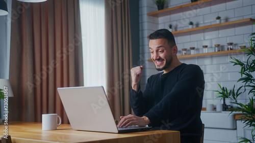 Bild auf Leinwand Adult man sitting in the kitchen checking emails read notice receive good news w