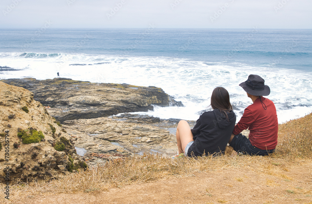 pareja de turistas descansa y mira el borde costero en un día libre