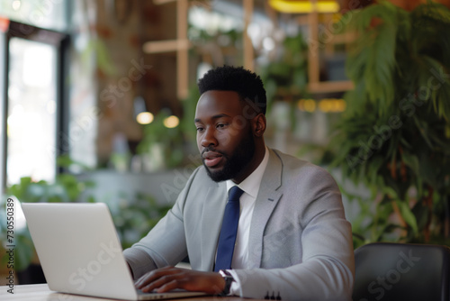 Determined Young African American Professional Focused on Laptop in Eco-Friendly Office