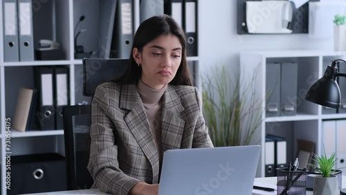 Puzzled, troubled caucasian woman office worker in doubt shrug shoulder working with laptop at desk in the modern office environment. photo