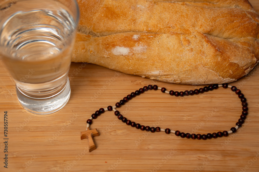 acercamiento de pan y agua y rosario listos para el ayuno para ayunar en cuaresma signos religiosos católicos sacrificio y oración - obrazy, fototapety, plakaty 