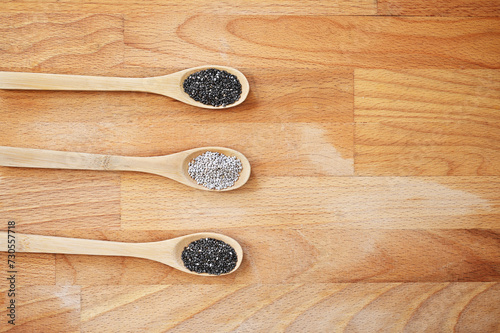 White and black Chia seeds on three spoons on a wooden board, with negative space