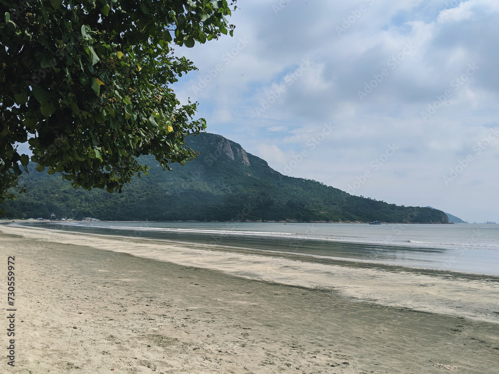 A tranquil beach scene with calm waters and a mountainous backdrop. A tranquil beach scene with calm waters and a mountainous backdrop.