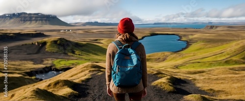 Hiking in Iceland. Woman with a backpack and a red hat on the background of the Icelandic landscape.