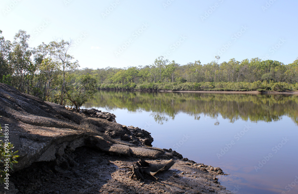 View of the Boyne River surrounded by trees and rocks at Boyne Island in Queensland, Australia