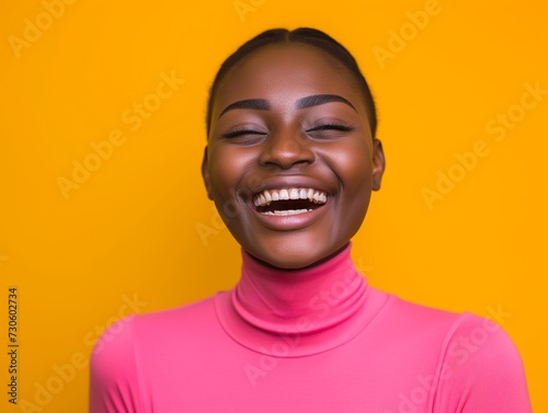 Vibrant image of a cheerful young African women laughing heartily, wearing a pink turtleneck against a vivid yellow backdrop.