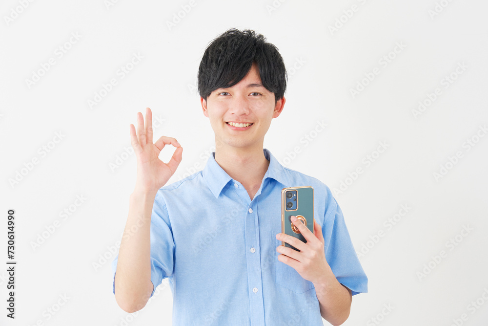 スマートフォンを持ってOKサインをする男性　白背景