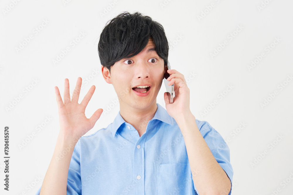驚きながらスマートフォンで電話する男性 白背景 驚きながらスマートフォンで電話する男性 白背景