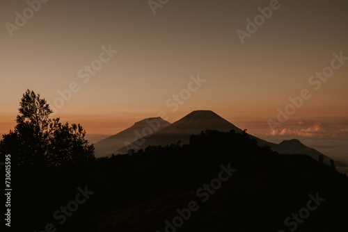 Scenery background of the view of orange sky with the mountain silhouette in the time of sunset or sun rise at the top of prau mountain in wonosobo city Indonesia