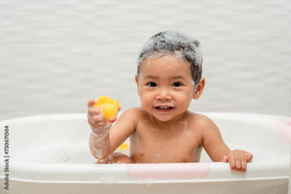 happy infant baby take a bath and playing rubber duck with foam bubbles in bathtub happy infant baby take a bath and playing rubber duck with foam bubbles in bathtub