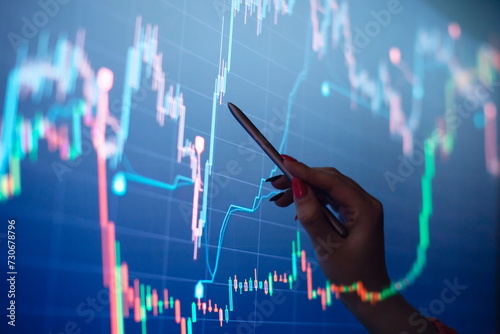 Businesswoman manually drawing a diagram on a touch screen interface. Stock market concept