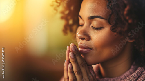 Portrait of black woman praying or meditating, holding hands in front of her. Composed with copy space.