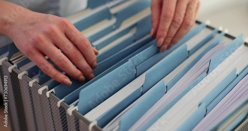Female office worker takes documents in blue folder from box photo