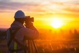 surveyor with theodolite in sunsetlit construction field