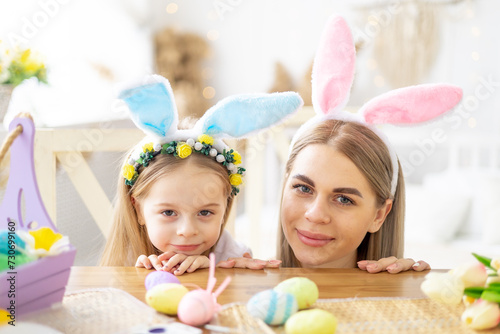 easter, mom and little daughter with bunny ears on their head are preparing for the holiday by having fun playing and spending time together, colorful eggs, lifestyle,
