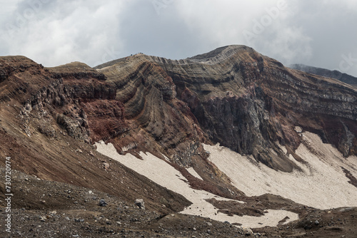 Majestic mountain landscape. The rim of a volcanic crater. View of the rock layers on the inner slope of the volcano's crater. Nature of the Russian Far East. Gorely volcano, Kamchatka Krai, Russia. photo