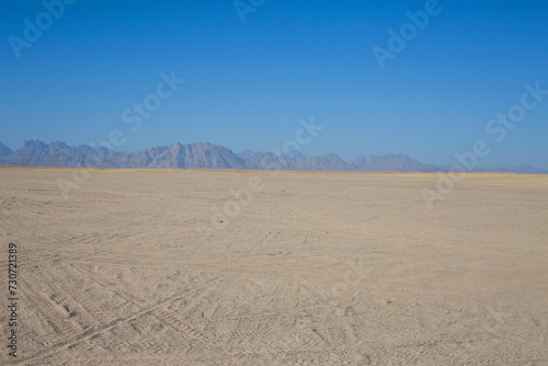 Horizon of sandy desert against the backdrop of clear sky and sandy mountains in the distance