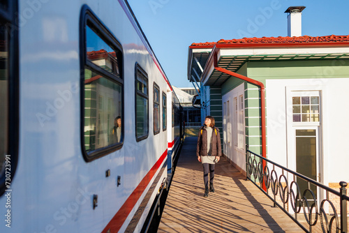 young girl with a backpack walks along the station platform.