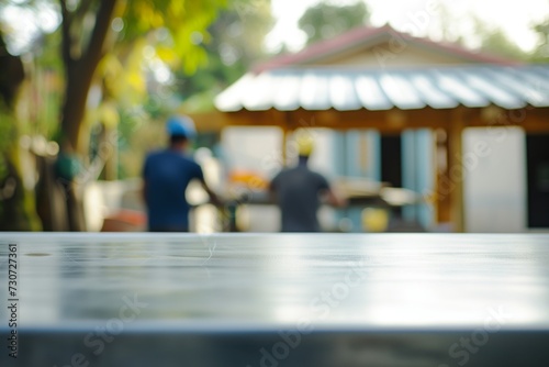 uncluttered steel table, craftsmen setting up a roof blurred in the background photo