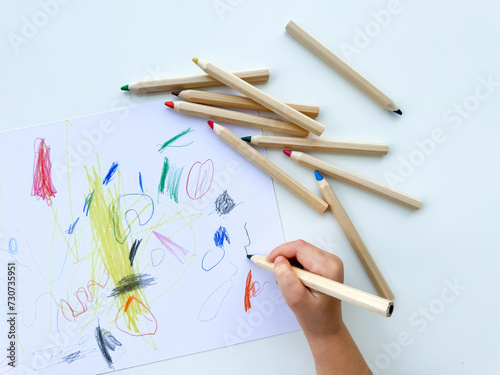 Wallpaper Mural small child draws with colored pencils on paper on white table. Torontodigital.ca