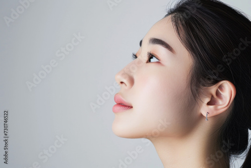 Serene young woman with minimalist jewelry looking upwards. Beauty and elegance.