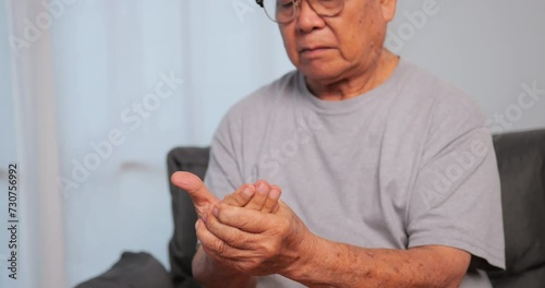 An elderly Asian man has tingling and numbness in his hand which causes beriberi. photo