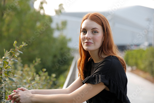 Happy ginger woman smiling and looking at camera while walking green park in the afternoon for relaxing