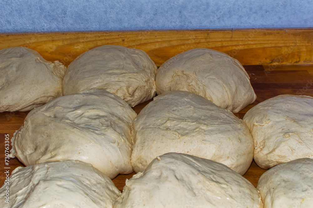 Fresh bread dough resting at wooden table in bakery.