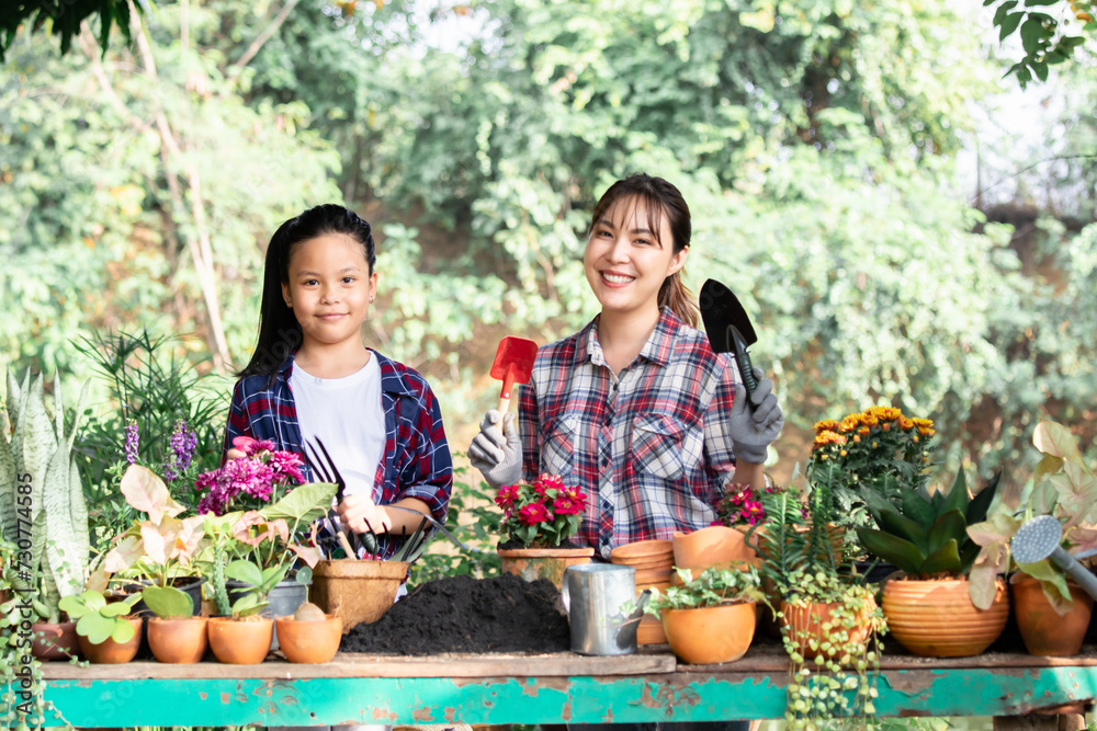 Asian sibling gardeners help plant trees together at the farm, favorite family hobby. Mom and little girl planting seedling in ground in garden, Eco-friendly. Kid help nanny work in garden on holiday. Asian sibling gardeners help plant trees together at the farm, favorite family hobby. Mom and little girl planting seedling in ground in garden, Eco-friendly. Kid help nanny work in garden on holiday.
