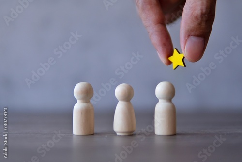 Hand holding a star over the team. Awarding, appreciation and reward for employees concept. photo