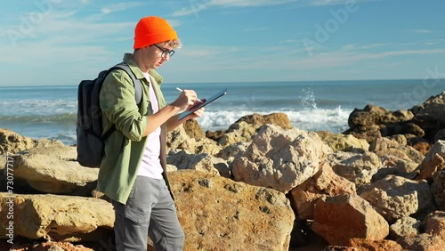 Young senior marine biologist takes notes digital tablet, boy is analyzing sea water in the mediterranean sea. Study of scientific statistics. photo