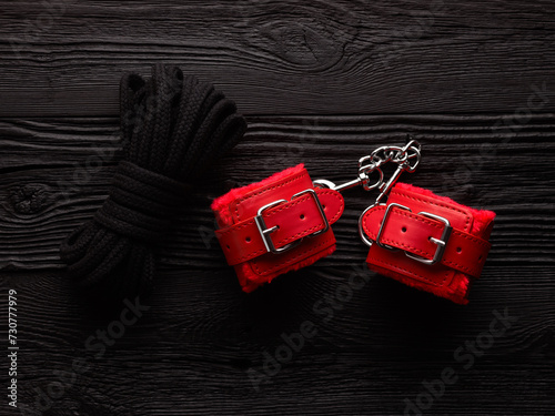BDSM background with bright red fluffy handcuffs and rope for tying