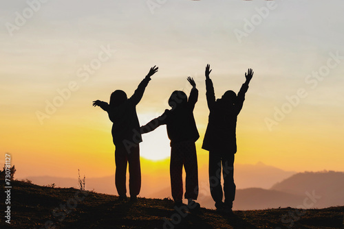 Silhouette, group of happy children playing on mountain sunset background