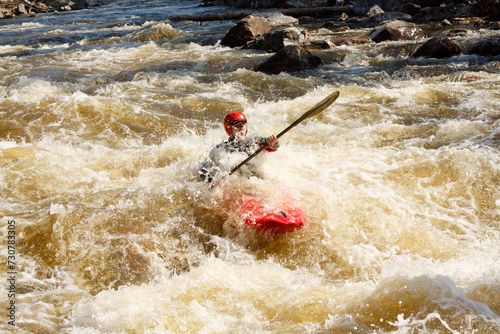 Adventurous Man in Red Kayak in Turbulent River with Lush Forest and Rocks