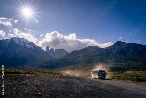 A bus driving to torres del paine national park with tree base tower mountain as background  and beautiful sun flare (Patagonia, Chile) © Puwaphat