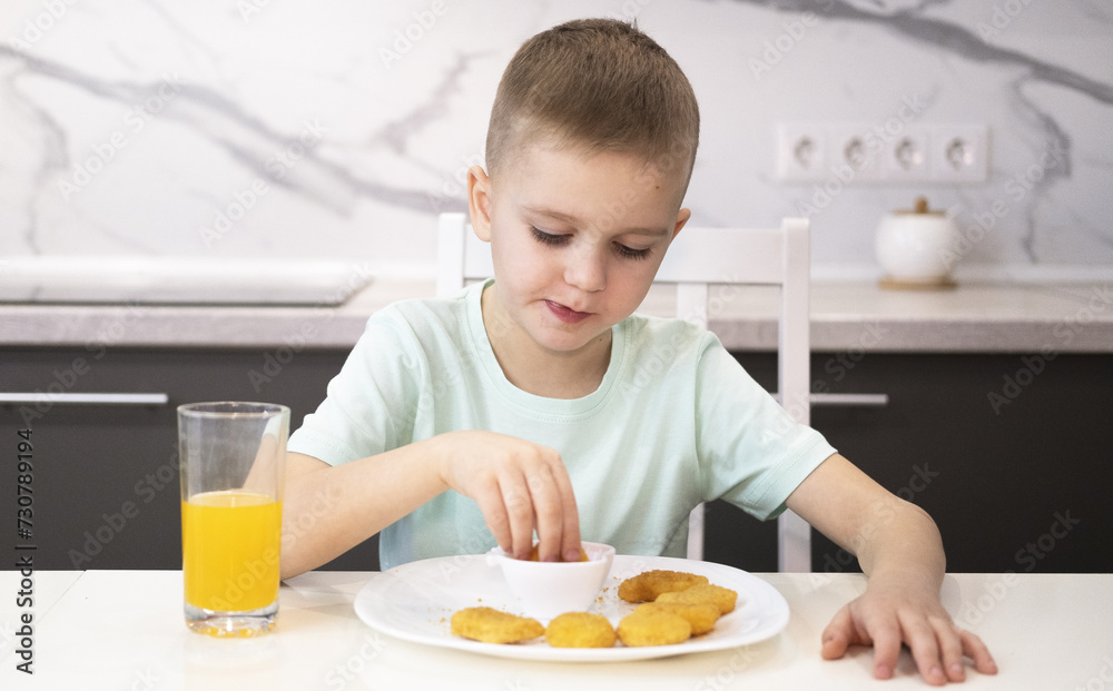 Happy child eating fast food at home chicken nuggets. Boy eats junk food at home. Happy child eating fast food at home chicken nuggets. Boy eats junk food at home.