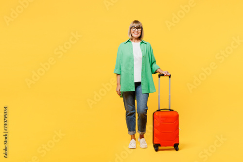 Full body traveler elderly woman wear green casual clothes hold suitcase bag isolated on plain yellow background. Tourist travel abroad in free spare time rest getaway Air flight trip journey concept #730795354