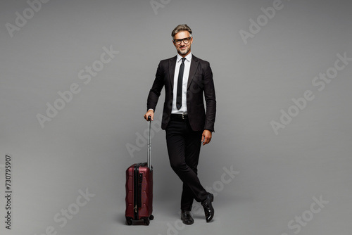 Traveler employee business man corporate lawyer wear black suit hold suitcase bag isolated on plain grey background. Tourist travel abroad in free time rest getaway. Air flight trip journey concept. #730795907