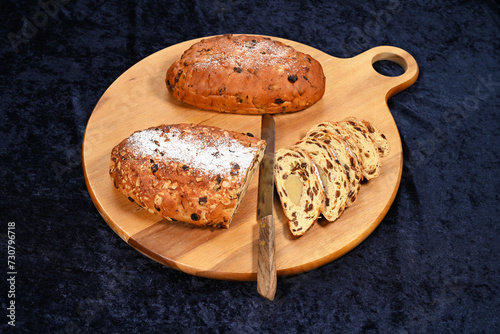 Christmas stollen served on a wooden board. Kerststol is a traditional Dutch oval-shaped fruited Christmas bread is eaten during the holidays