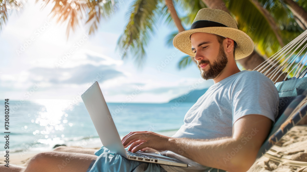 Fototapeta premium A man wearing a straw hat working on a laptop while sitting on a hammock by the ocean, representing a remote working lifestyle. Ai generative