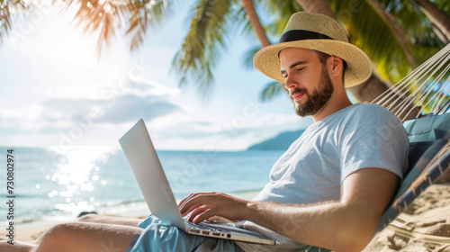 A man wearing a straw hat working on a laptop while sitting on a hammock by the ocean, representing a remote working lifestyle.  Ai generative photo